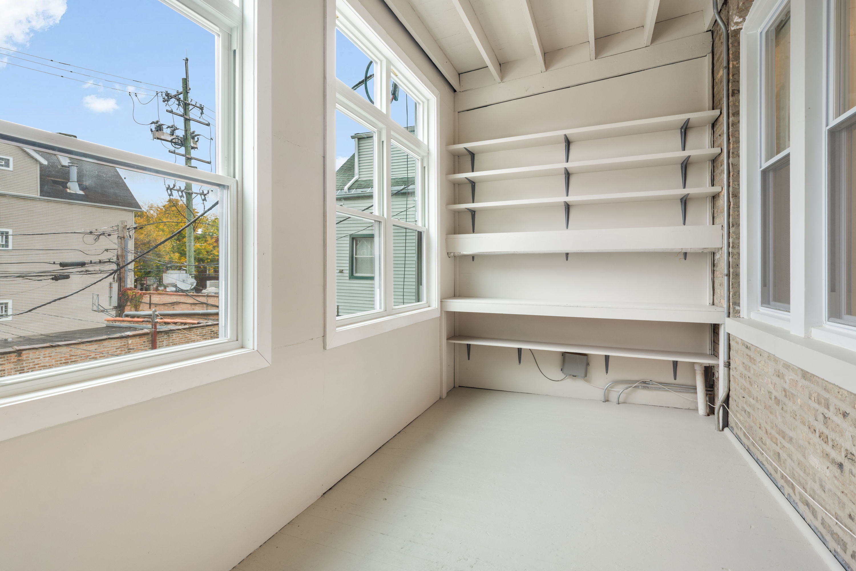 Enclosed sunroom with built-in shelving and windows on two sides